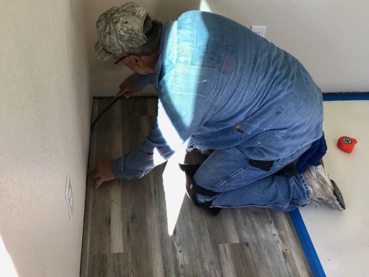 Gene sets the last piece of flooring in place