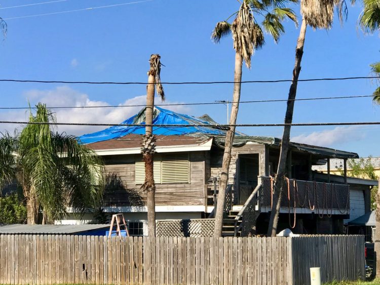 House with blue tarps on roof
